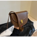 Close-up of brown leather saddle bag with gold buckle and stylish rivet strap detail - Brown