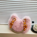 Rosa Kunstfell-Handtasche mit Holzperlengriff auf stilvollem minimalistischem Hintergrund - Rosa