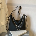 Black nylon shoulder bag with gold chain and pearl accents on a silver suitcase - Black