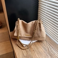 Braune Umhängetasche aus Wildleder mit Goldkette und Metallverschluss auf Holz - Khaki