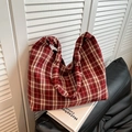 Détail du sac cabas en toile à carreaux rouges avec poignée à nœud sur livres et canapé - Rouge