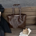 Vue détaillée du grand sac cabas marron foncé avec petite pochette sur un banc en bois - Marron