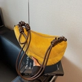 Borsa a mezzaluna in camoscio giallo con tracolla annodata su libro di design - Giallo