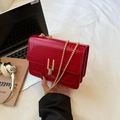 Red crocodile texture shoulder bag with golden chain and clasp on white bedding - Red