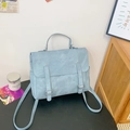 Light blue faux suede vintage satchel backpack with adjustable straps on dark surface - Blue