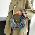 Irisierende metallische Seil-Handtasche mit Knotengriff in der Hand gezeigt - Bunt