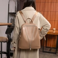 Sac à dos en cuir kaki avec fermeture en V porté par un mannequin en trench-coat beige - Kaki