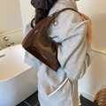 Dettaglio macro della borsa hobo in vernice color caffè con ciondolo a cuore in argento - Marrone