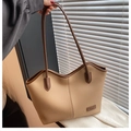 Close-up of a large tote bag featuring pebble grain faux leather and slim dark handles - Apricot