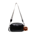 Minimalist black crossbody bag with geometric woven strap and plush monster charm detail - Black