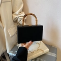 Elegante schwarze Box-Handtasche mit Bambusgriff und Goldkette in modischem Ambiente - Schwarz