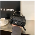 Detailed shot of black quilted crossbody bag featuring a silver twist lock and chain strap - Black