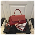 Detalle de bolso de mano rojo en cuero con cierre dorado y correa de hombro - Rojo