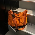 Fashionable bright orange nylon crossbody bag with large black buckle and drawstring detail - Orange