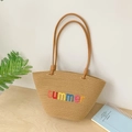 Sommer Strohtasche mit bunter Stickerei und schmalen braunen Henkeln auf Holztisch - Braun