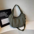 Bolso tote grande de nailon verde oliva con correa ancha sobre un soporte blanco - Verde