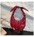 Détail du sac en cuir verni bordeaux avec oillets métalliques et poignée en noud - Rouge