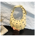 Detail of a pale yellow hobo bag featuring silver metal grommets and a knot handle design - Yellow