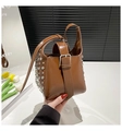 Détail du sac seau en cuir caramel avec rivets argentés et large sangle à boucle - Marron