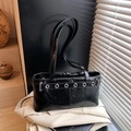 Borsa a spalla nera lucida con occhielli argentati su sfondo di giacca blazer - Senza Ciondolo / Nero
