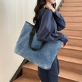 Große blaue Denim-Tragetasche mit schwarzem Gurt, am Model in modernem Interieur gezeigt - Blau