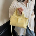 Borsa a mano minimalista in pelle verniciata giallo chiaro con tracolla indossata da modella - Giallo