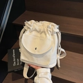 Off-white canvas drawstring bucket bag with silver metal buckle on a wooden step - Off White