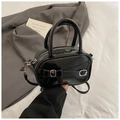 Close-up of black glossy leather handbag with silver buckles and elegant top handles - Black