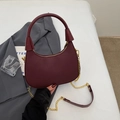 Dunkelrote gewebte Handtasche mit goldener Kette auf einem grauen Sakko getragen - Rot