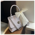 Detail of light purple handbag featuring metallic twist lock and lace bow accessory - Purple