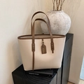 Close-up of litchi texture cream tote bag with dark brown handles on a wooden base - White