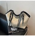 Détail latéral du grand sac cabas beige avec bordure noire sur un livre anglais - Kaki