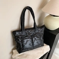 Black quilted tote bag with large front pockets and glossy padded fabric texture - Black