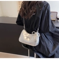 Borsa a tracolla argento con fiocco, catena di perle e ciondolo a cuore su modella - Argento