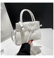 Detalle de bolso blanco de cuero con grano de lichi, hebilla metálica y asas superiores - Blanco