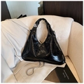Glossy black hobo bag with silver ball handle and chain strap on a sofa - Black