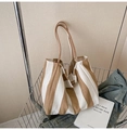 Detail of a large striped canvas tote bag inside a metal basket in a casual scene - Wide Stripe Khaki