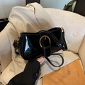 Borsa sottobraccio minimalista in vernice nera con fibbia dorata sul divano - Nero