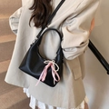 Detail of black matte leather crescent bag with pearl and checkered bow charm - Black