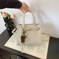 Elegante borsa tote in pelle bianco crema con chiusura a scatto argento su un libro - Beige