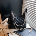 Black quilted crossbody bag with pearl and rhinestone chains on a blazer background - Black