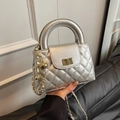 Silver quilted small square handbag with gold chain strap and rotary lock shown held by hand - Silver