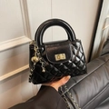 Close-up of black quilted leather handbag with gold metal clasp and chain strap detail - Black