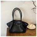 Detailansicht der schwarzen Plissee-Ledertasche mit goldener Schnalle auf Holztisch - Schwarz