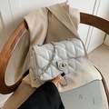 Light grey quilted crossbody bag with silver chain strap on a wooden chair - Blue