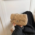 Beige quilted small square bag with silver chain strap shown held by a model - Khaki