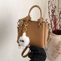 Brown lychee leather tote bag with monster charm and knotted handle on neutral background - With Plush Monster Charm / Khaki
