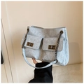 Sac moto en denim bleu avec bandoulière chaîne et doubles poches tenu à la main - Bleu clair