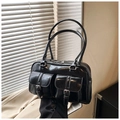 Dettaglio della borsa Boston in vernice nera lucida con tasche a fibbia e doppi manici sottili - Nero
