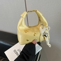 Metallic yellow hobo bag with gold handle and playful charms in a stylish hand-held pose - With Pendant / Yellow